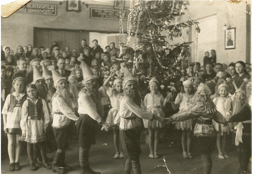 Nuotrauka, kurioje vaikų, sustojusių ratu, būrys, per vidurį - papuošta eglutė